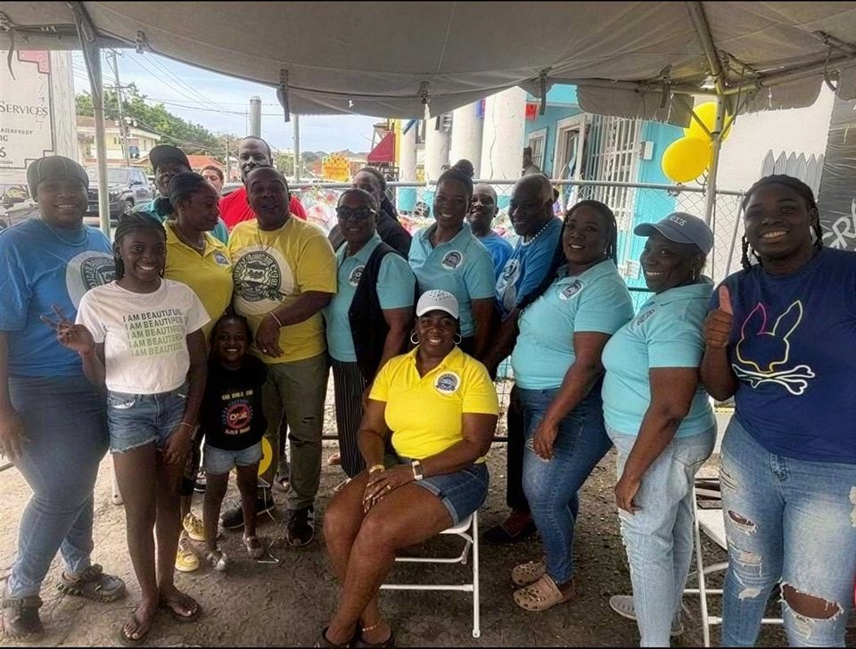 Volunteers in United Against Crime shirts and a few children pose together under a tent at the Easter event